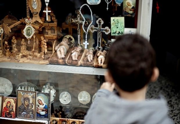 un garçon regarde des figurines de l’Enfant Jésus exposées dans un magasin de la ville biblique de Bethléem