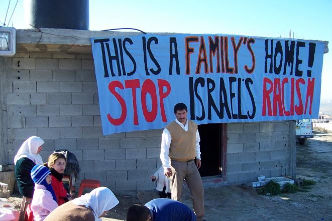 Des habitants palestiniens devant leur maison pour empêcher sa destruction par les forces israëliennes. © ICAHD