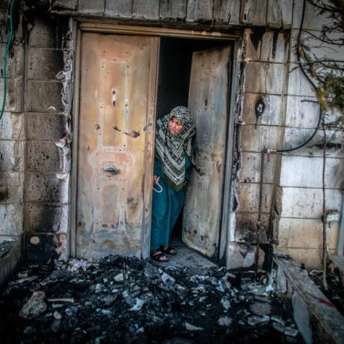Une Palestinienne examine lexterieur de sa porte incendie par des colons juifs a Huwwara en Palestine occupee le 26 fevrier 2023 Les appels israéliens au génocide accueillis dans l’indifférence générale à Washington et à Bruxelles