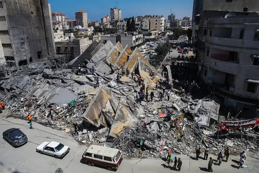 Assassinats de masse : les bombardements calculés d'Israël sur Gaza — Des Palestiniens se rassemblent autour des restes d'une tour abritant des bureaux qui, selon des témoins, a été détruite par une frappe aérienne israélienne dans la ville de Gaza, le 26 août 2014. (Emad Nassar/Flash90)