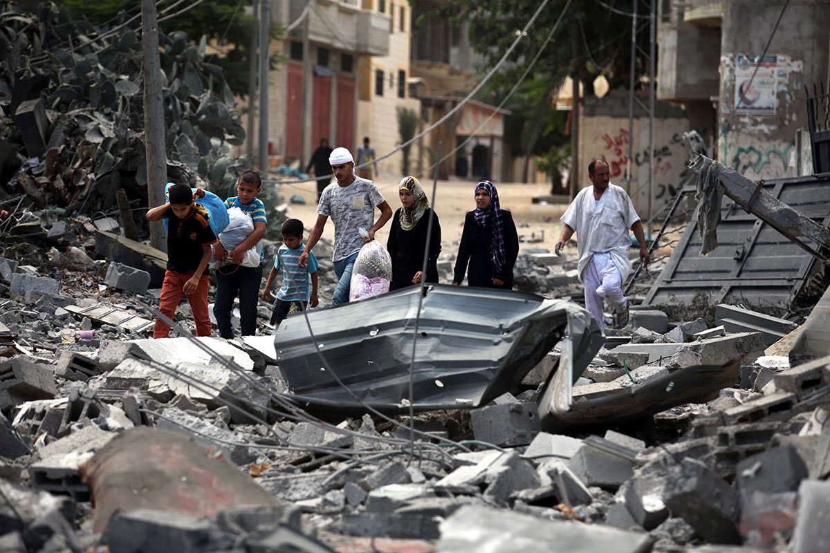 Une famille palestinienne s’avance à travers les décombres de ce qui était leur maison.