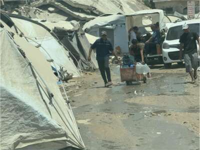 Photo les gens transportent de l'eau potable sur un site de déplacement dans le centre de Gaza.