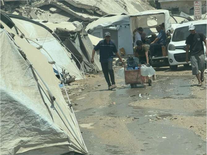 Photo les gens transportent de l'eau potable sur un site de déplacement dans le centre de Gaza.
