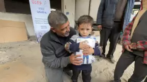 Témoignage d'Abu Amir, le 16 décembre 2025 - À Gaza le métier de pêcheur saigne 12 un enfant et un homme devant une bannière UJFP